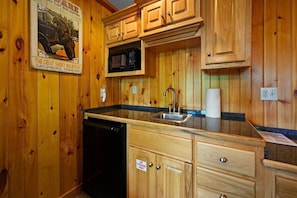 A wooden cabin-style kitchen with a built-in microwave, sink, and a dishwasher.