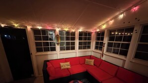 Ein gemütliches Zimmer mit einem roten Ecksofa, einem gemusterten Teppich und Lichterketten.
