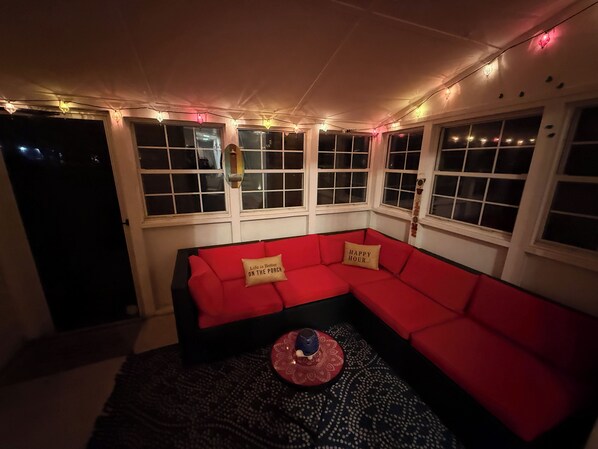 Una habitación acogedora con un sofá seccional rojo, alfombra estampada y luces colgantes.