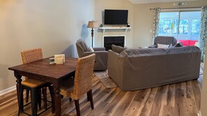 Ein gemütliches Zimmer mit Esstisch, Stühlen, einer Couch, einem Bett, einem Fernseher und einem Kamin.