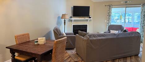 A cozy room with a dining table, chairs, a sofa, a bed, a TV, and a fireplace.