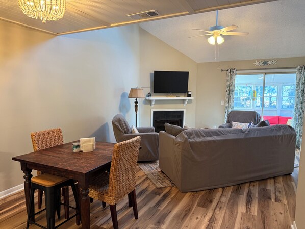 Ein gemütliches Zimmer mit Esstisch, Stühlen, einer Couch, einem Bett, einem Fernseher und einem Kamin.