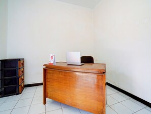 A wooden desk with a laptop and a sign on it, a black filing cabinet, and a tiled floor. - Spot ON 90200 Pondok Sabaraya Cileunyi Syariah (Cileunyi)