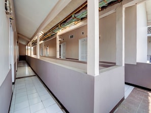A long corridor with white tiled floors and walls, leading to multiple doors. - Spot ON 90200 Pondok Sabaraya Cileunyi Syariah (Cileunyi)