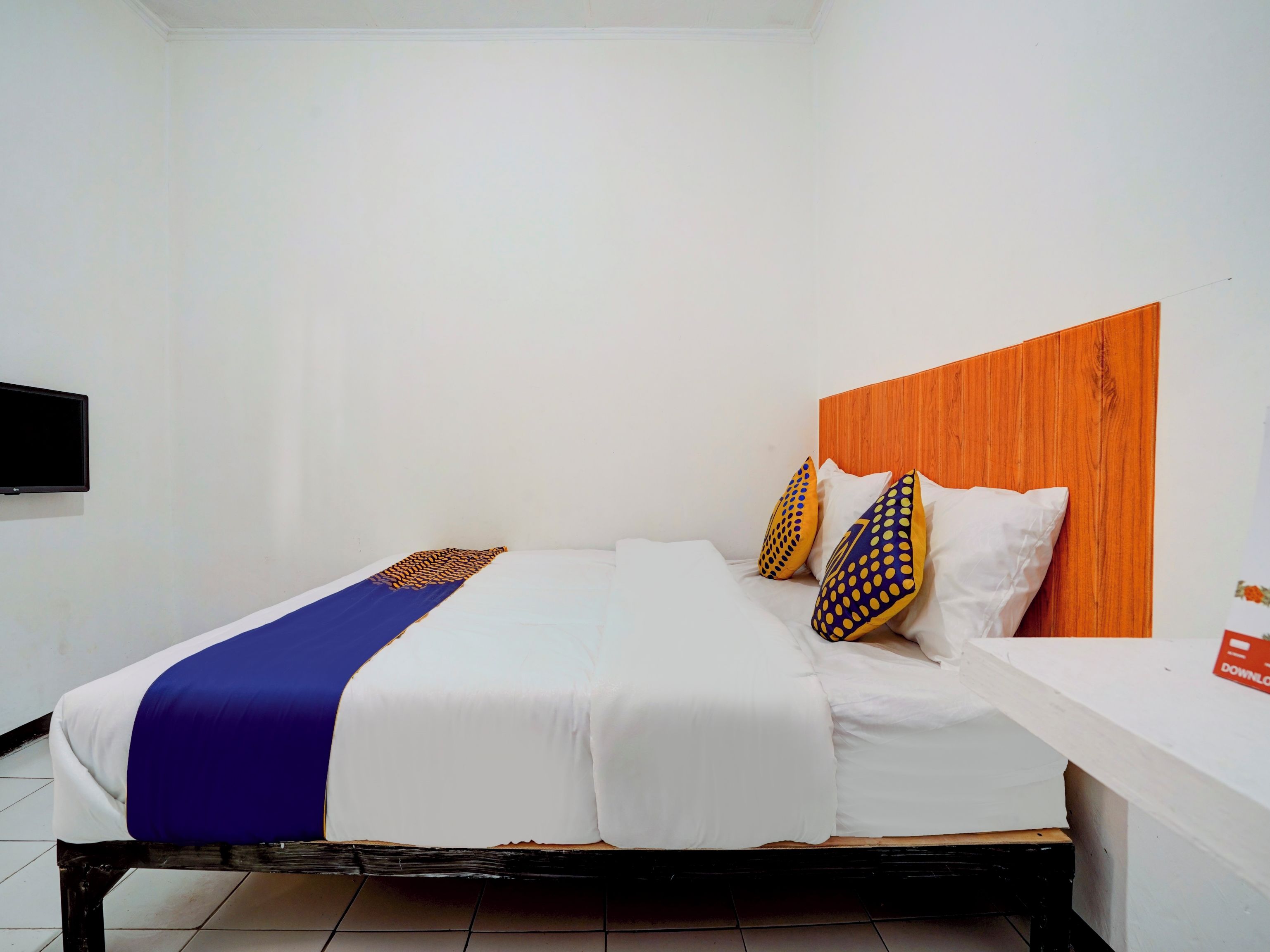 A bed with white bedding, a blue and gold throw, and patterned pillows.