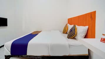 A bed with white bedding, a blue and gold throw, and patterned pillows.