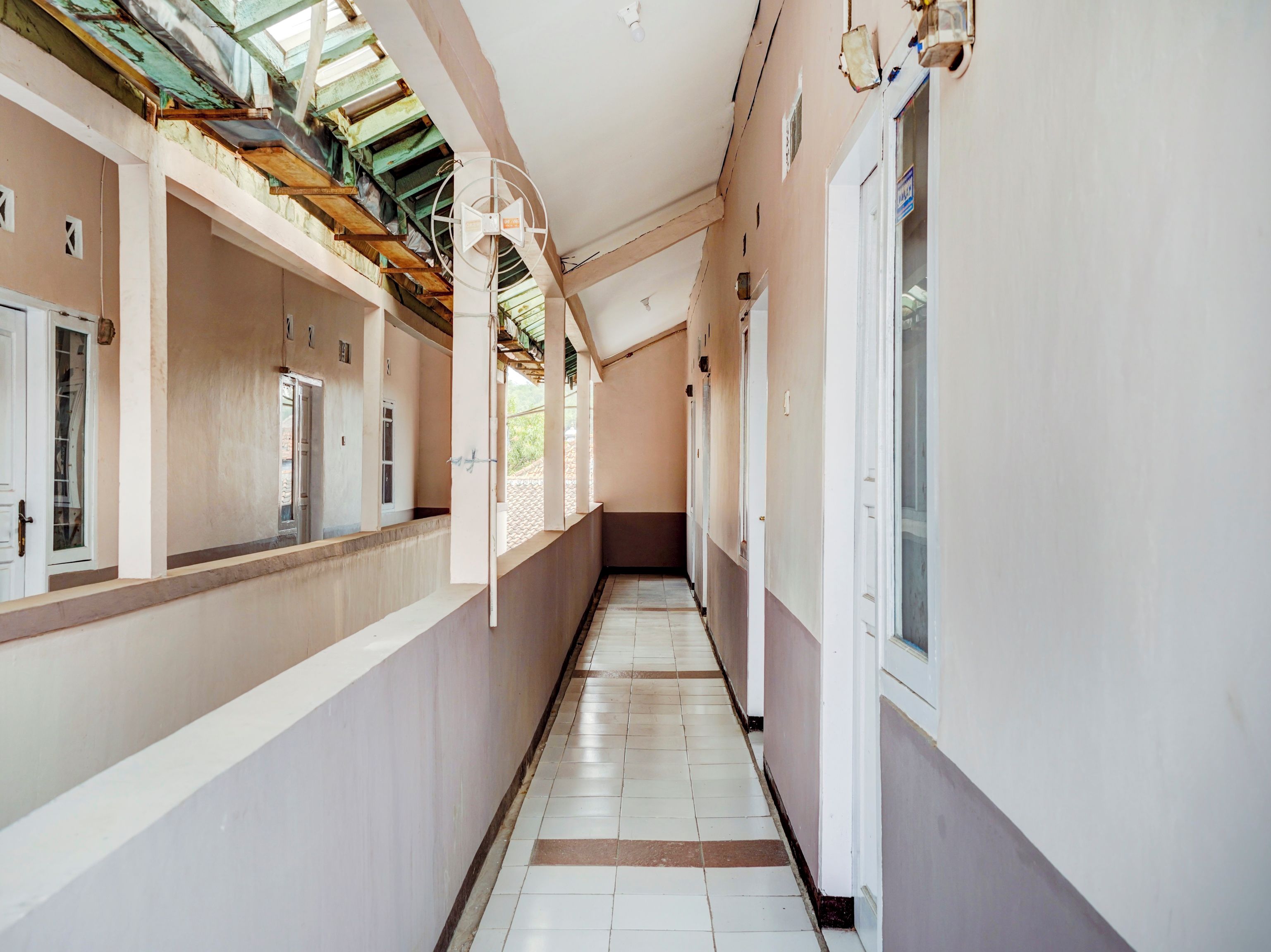 A corridor with a tiled floor, white walls, and a ceiling with exposed beams.