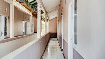 A corridor with a tiled floor, white walls, and a ceiling with exposed beams.