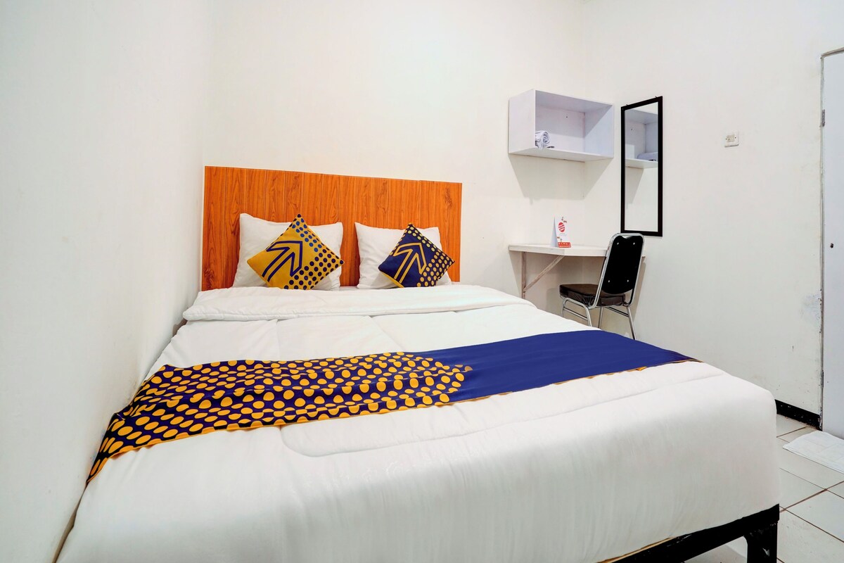 A hotel room with a bed, a desk, and a chair.