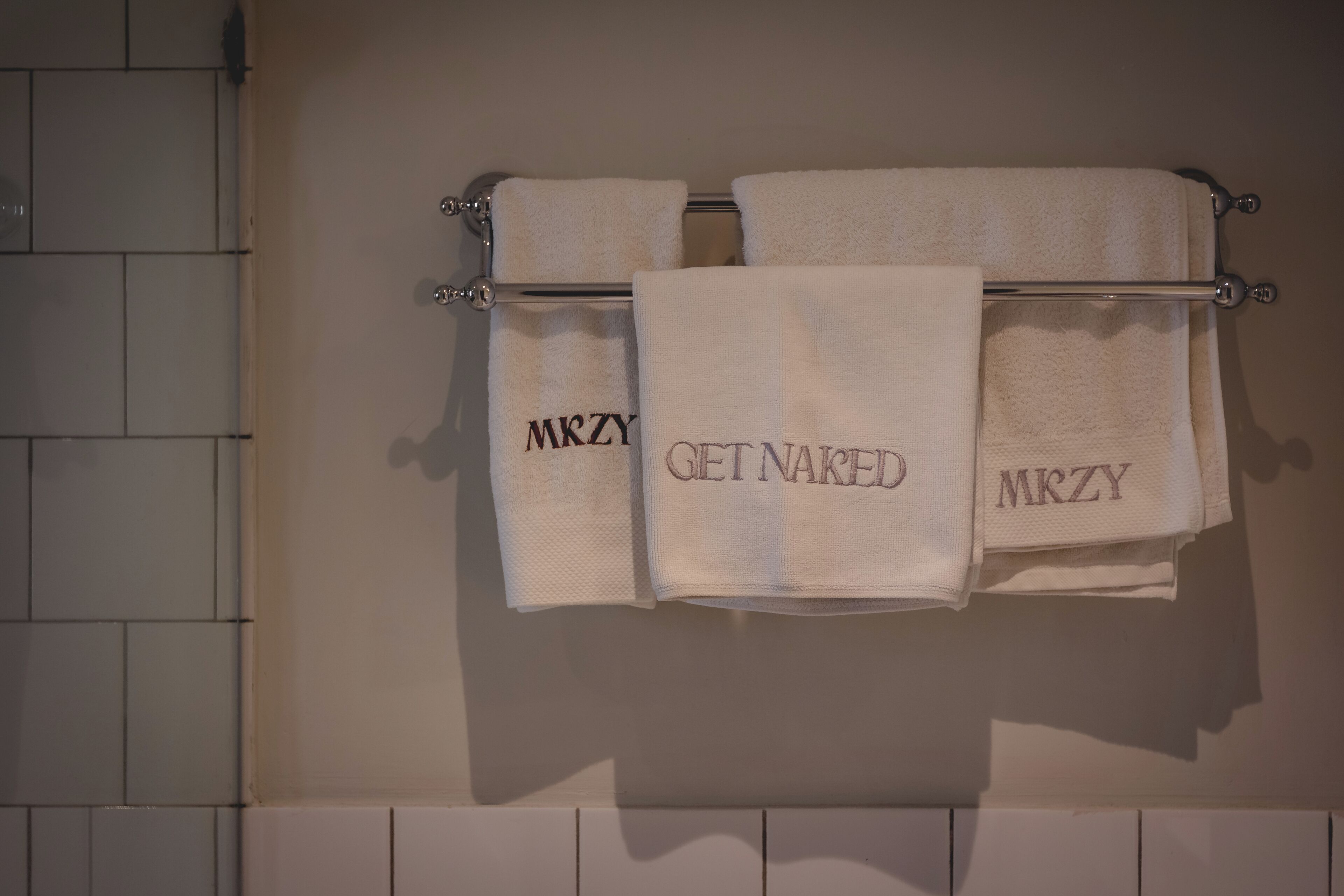 A bathroom with a towel rack holding three towels.