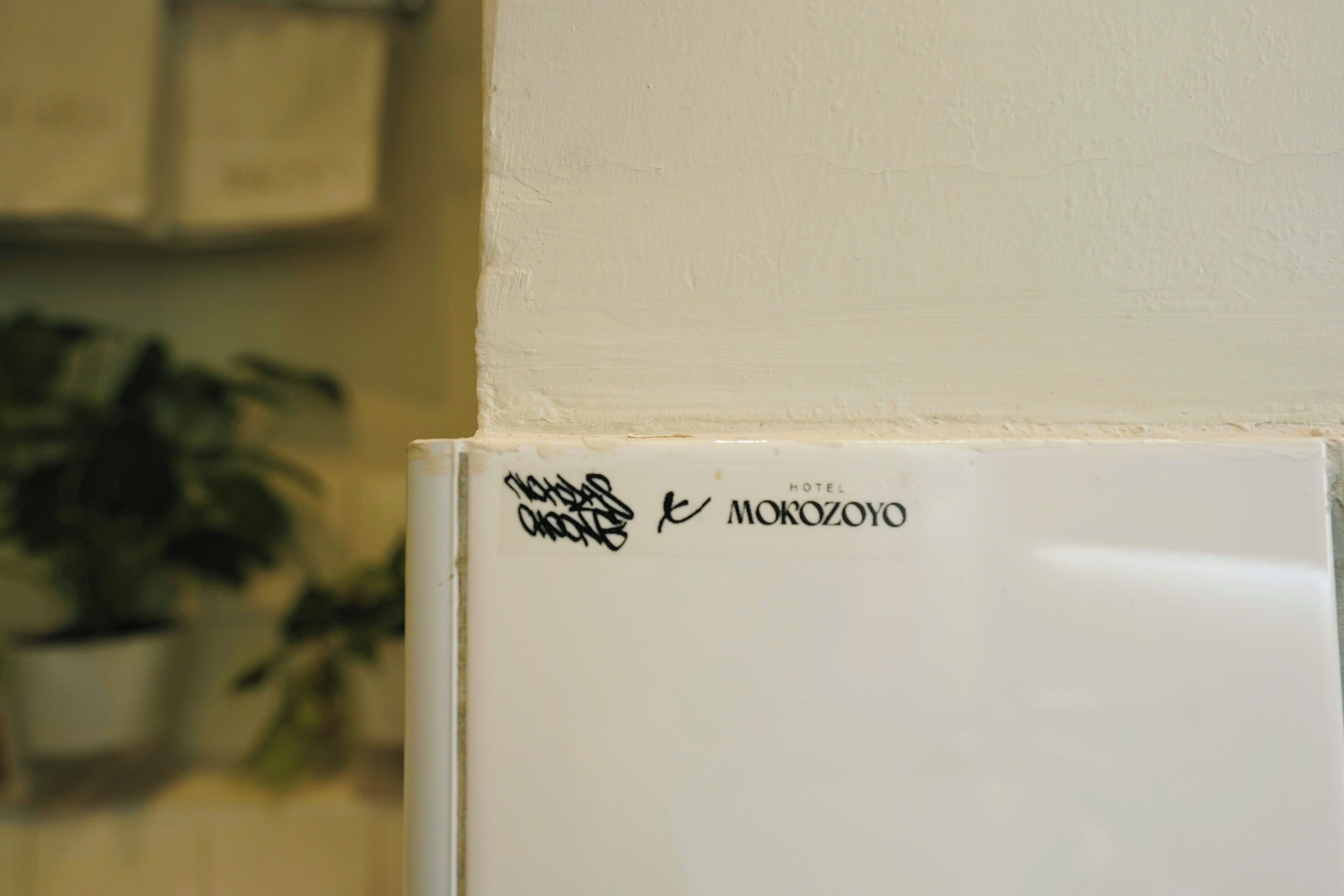 A white refrigerator with a sticker that reads 'Hotel Mokozoyo.'