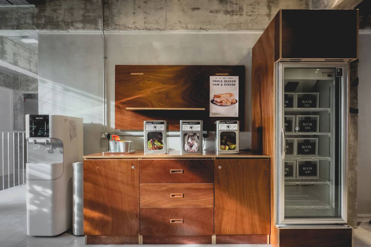 A kitchenette with a wooden cabinet, a refrigerator, and a glass-fronted storage unit.