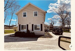 A two-story house with a front porch, a garage, and a parked SUV. - Limestone Corner Bungalow (Graytown)