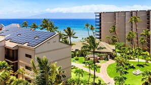 A hotel with solar panels on the roof, a pool area, and a view of the ocean.