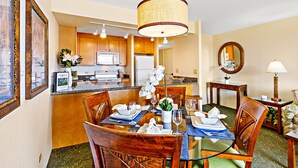 Une salle à manger d’hôtel avec une table en bois dressée pour quatre personnes, une cuisine en arrière-plan et un miroir au mur.