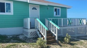 Stroll up to the charming front door, complete with a small window above, and ascend the stairs to the inviting porch.