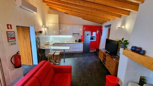 Une cuisine moderne avec des meubles blancs, un réfrigérateur rouge et un plafond en bois.