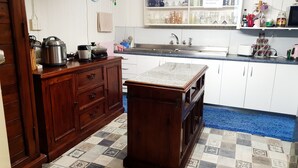 A kitchen with wooden cabinets, a sink, and a tiled floor. - Meyenburg Luxury Tent with shared bathroom/kitchen/lounge (Mount Morgan)