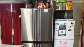 A compact kitchen with stainless steel appliances, a refrigerator with a Dosa sticker, and a microwave on top. - Meyenburg Luxury Tent with shared bathroom/kitchen/lounge (Mount Morgan)