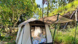 A tent with a canopy, a bed with floral bedding, and a leaf-patterned mat. - Meyenburg Luxury Tent with shared bathroom/kitchen/lounge (Mount Morgan)