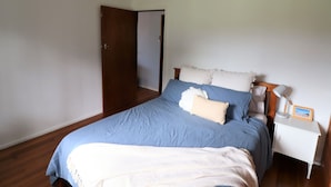 A bedroom with a bed, a nightstand, a lamp, and a door. - 9 Bastion Point Road (Mallacoota)
