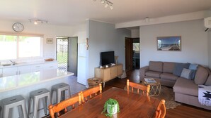 A modern living space with a kitchen, dining area, and living room. - 9 Bastion Point Road (Mallacoota)