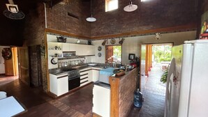 Een ruime keuken met een groot schiereiland, houten vloeren en een bakstenen wand.