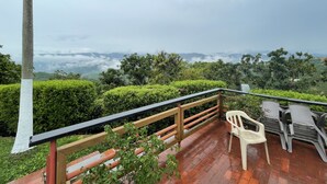 Een terras met houten balustrade, een tafel en twee stoelen.