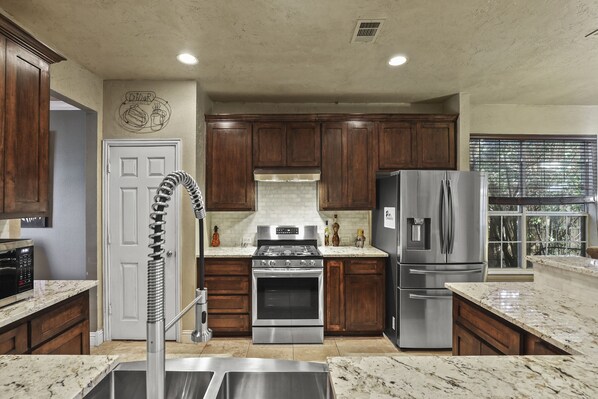 A modern kitchen with wooden cabinets, stainless steel appliances, and a granite countertop. - Luxury Home updated kitchen / Spa Bathrooms / and Grand Theater for movie night! (The Colony)