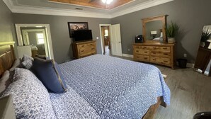 A bedroom with a bed, wooden dresser, ceiling fan, and a painting on the wall. - Peaceful Cabin Overlooking the Bogue Chitto River (franklinton)