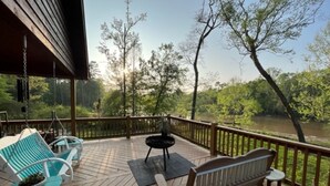 A wooden deck with outdoor furniture, a fire pit, and a view of a river and trees. - Peaceful Cabin Overlooking the Bogue Chitto River (franklinton)