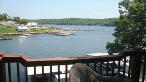A waterfront view from a balcony with boats docked in the background and a grassy area with buildings. - Lake front with orovate dock located in same cove as Coconuts!!! (Gravois Mills)