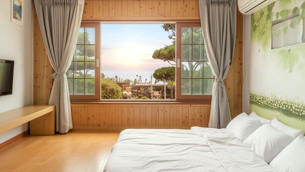 Un dormitorio con un ventanal que ofrece vistas al mar y a los árboles.