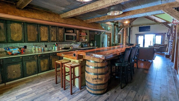Eine rustikale Küche mit Holzschnitzhäuschen, einer Bar mit Hockern und einem großen Holzfass.