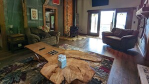 Ein rustikales Wohnzimmer mit einem großen Holztisch, zwei Sofas, einem Kamin und einer Steinwand.