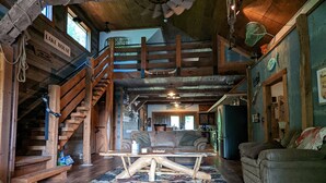 Ein rustikaler Innenraum mit einer Holztreppe, einem großen Couchtisch aus Holz und einem Sofa.
