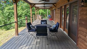 Eine Holzterrasse mit überdachtem Patio, komplett mit Tisch und Stühlen, und Blick auf die umliegende Natur.