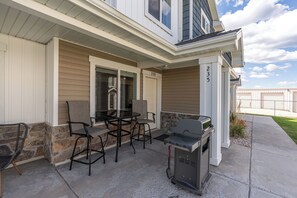 Eine Terrasse mit Gartenmöbeln und Grill, eine Steinmauer und die Hausnummer 235.
