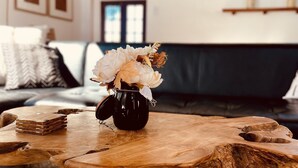 A wooden coffee table with a vase of flowers in a black pot. - Secluded 1 acre Mountain Home - Hot Tub, 3 Decks & Direct National Forest Access (Idyllwild-Pine Cove)