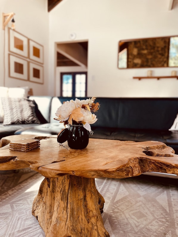 Una mesa de centro de madera con un florero de flores en una maceta negra.