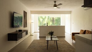 Uma sala de estar moderna com televisão de tela plana, uma mesa de centro com uma planta e um ventilador de teto.