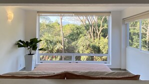 Quarto com uma janela grande, uma cama e um vaso de planta.