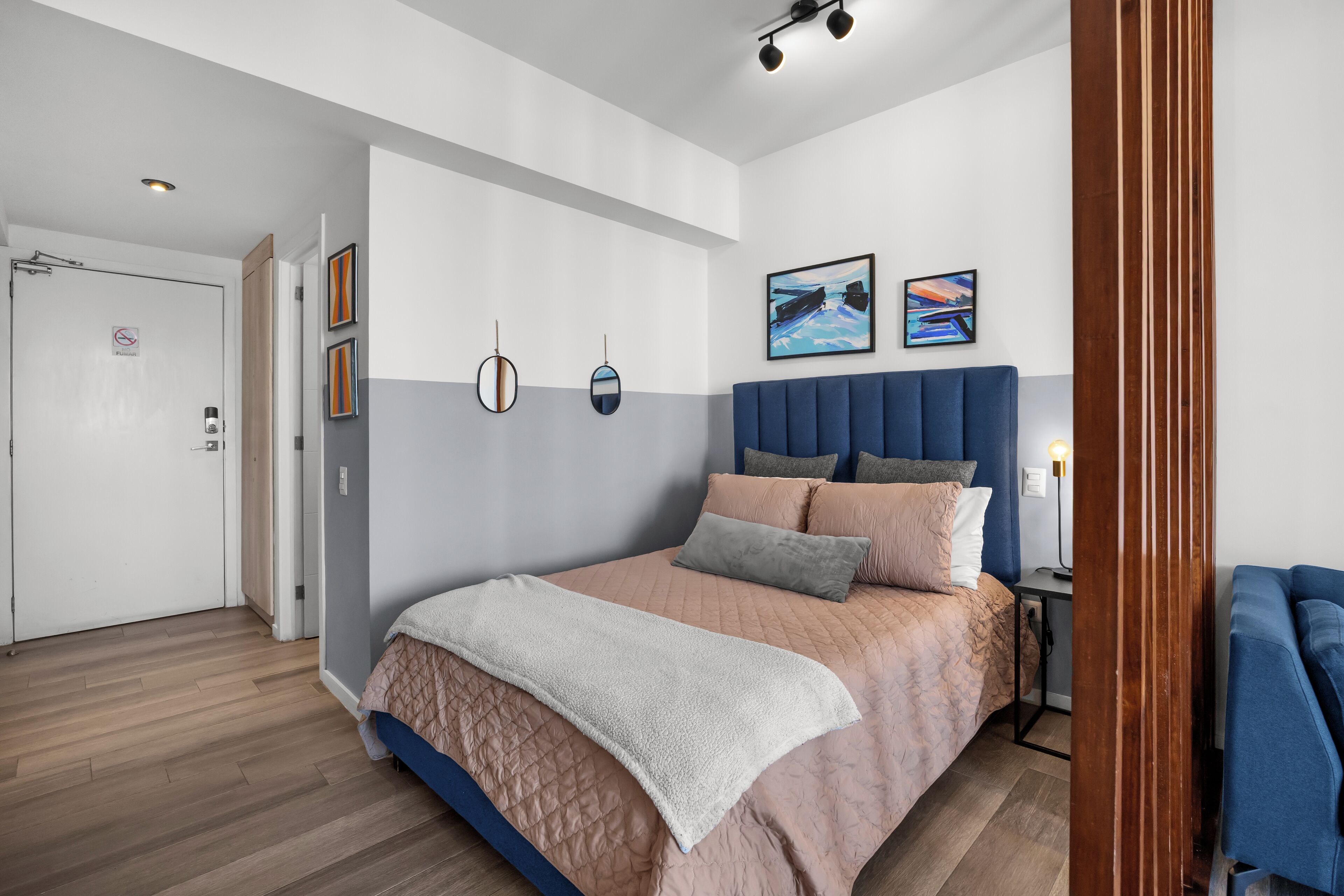A modern bedroom with a large bed, a bedside table, and a blue chair.