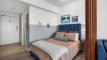 A modern bedroom with a large bed, a bedside table, and a blue chair.