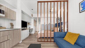 Ein zeitgemäßer Wohnbereich mit Küche, Essbereich und Schlafzimmer, abgetrennt durch eine Holzwand.