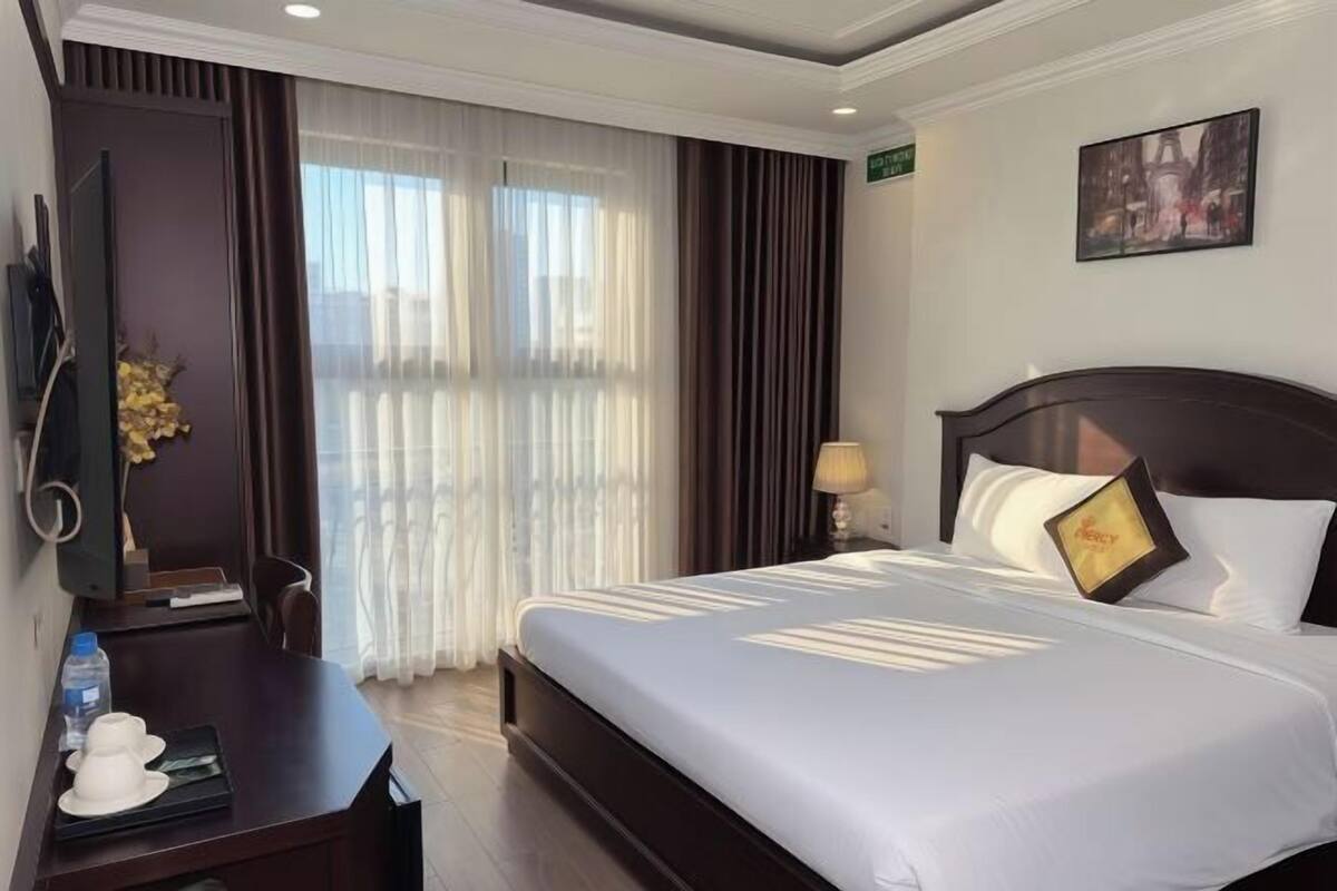 Una habitació d'hotel amb un llit, una taula de treball, una televisió i un quadre a la paret.