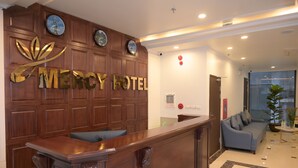 Un mostrador de recepción con un panel de madera de fondo y un gran letrero que dice 'Mercy Hotel'.
