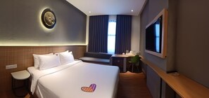 A hotel room with a large bed, a desk, a chair, a TV, and a window with curtains. - MaxOne Loji Kridanggo at Boyolali (Boyolali)