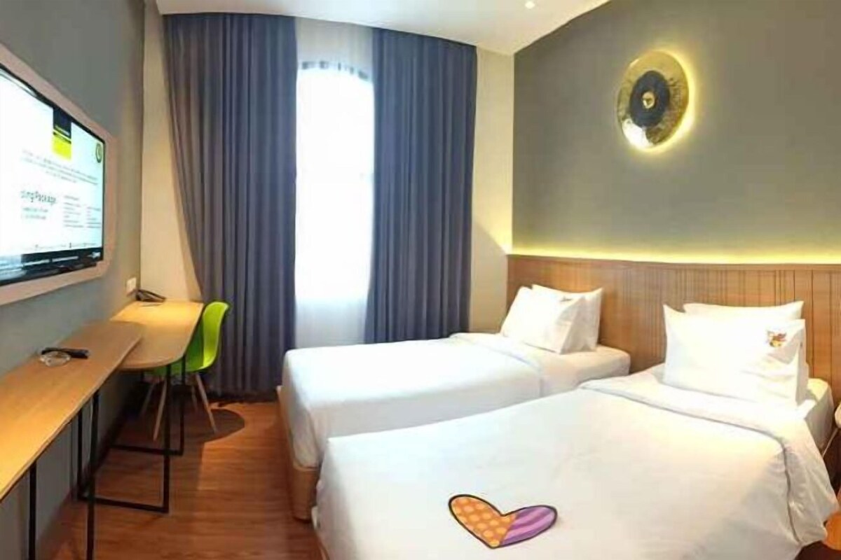 A hotel room with two beds, a desk, and a chair.