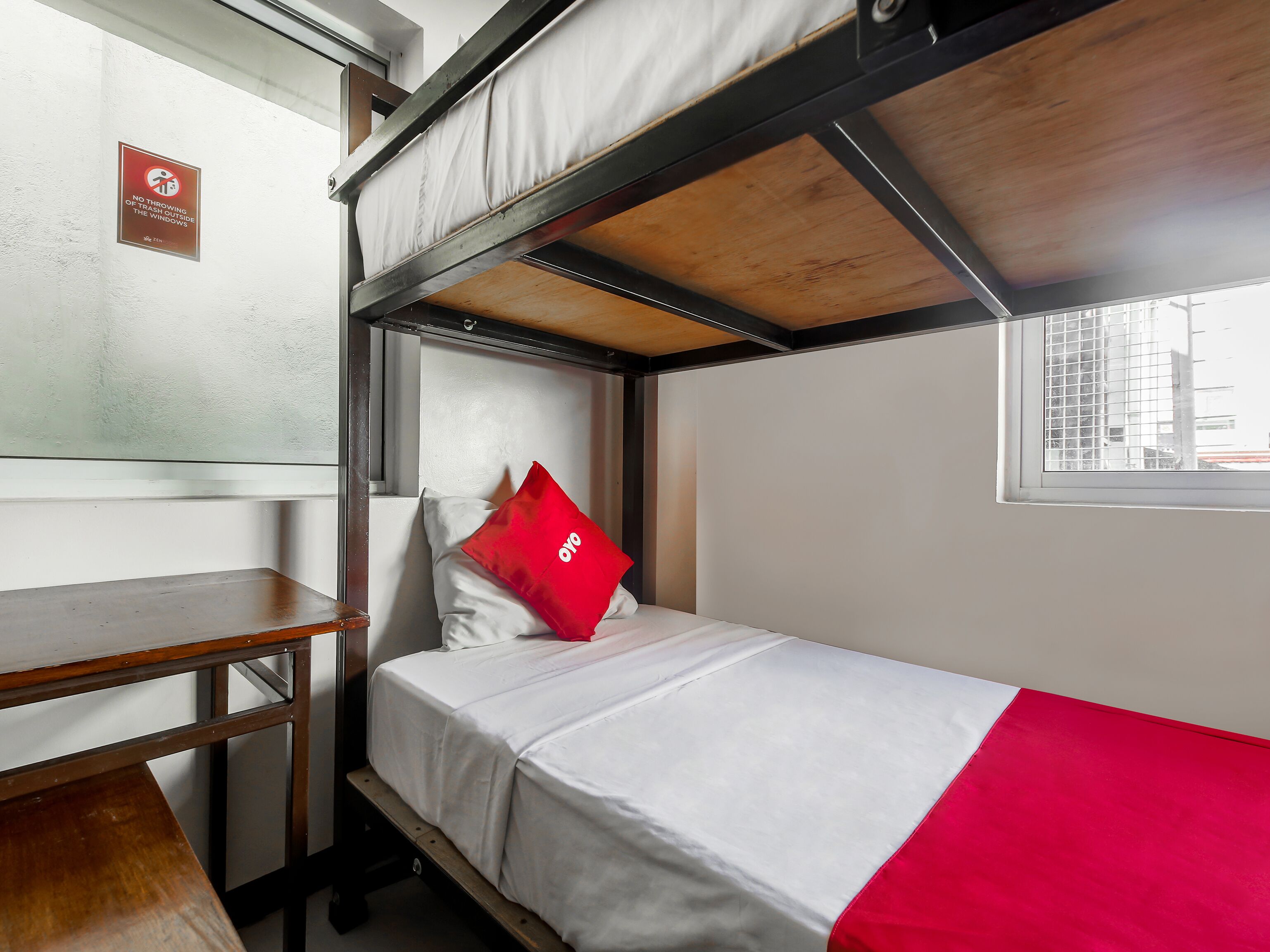 A bunk bed room with a desk and a window.